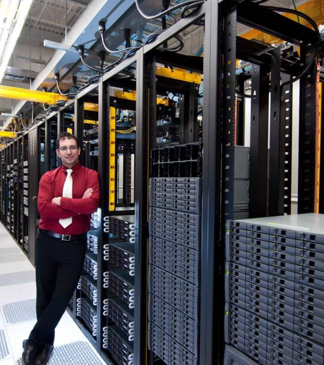 A happy datacenter manager looking at his datacenter equipment with a smile.